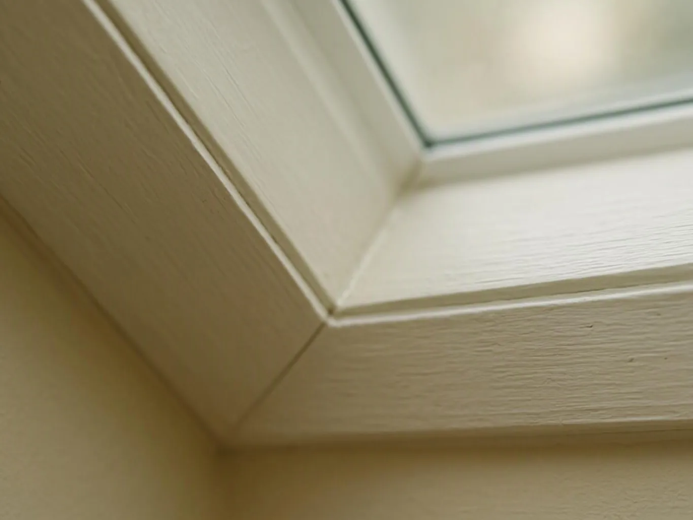 Close-up of a cream-painted window frame and corner of a glass pane inside a room