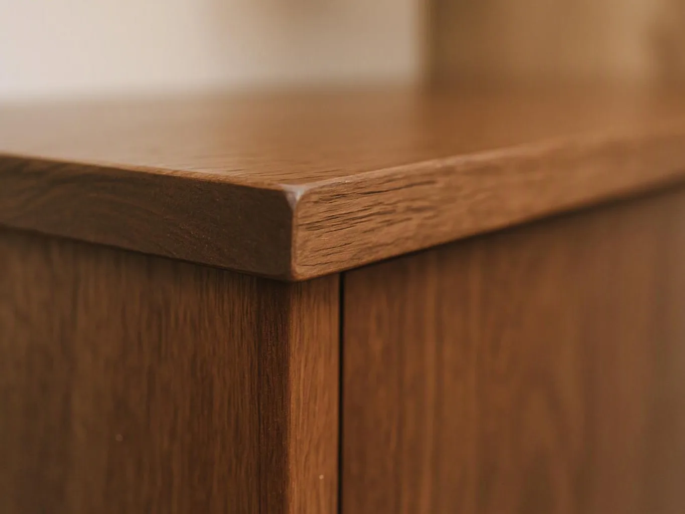 Close-up of a wooden cabinet corner with a smooth top and visible grain lines